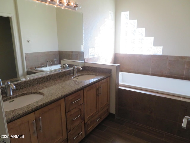 bathroom with tiled tub and vanity