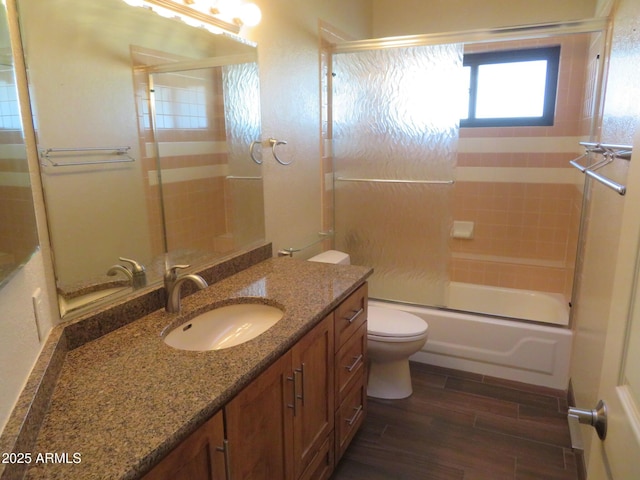 full bathroom with toilet, vanity, combined bath / shower with glass door, and hardwood / wood-style floors