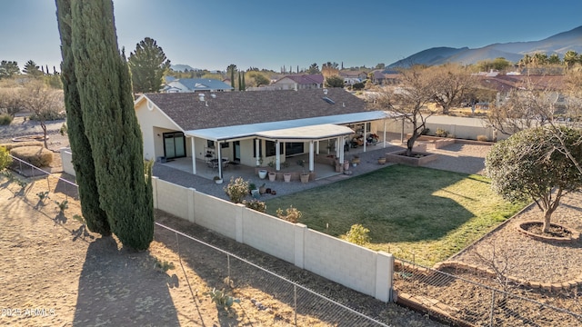 back of house featuring a mountain view, a patio, and a lawn