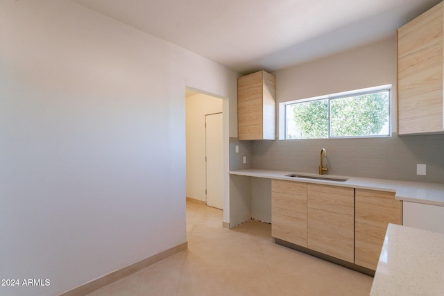 kitchen with backsplash, sink, and light brown cabinetry