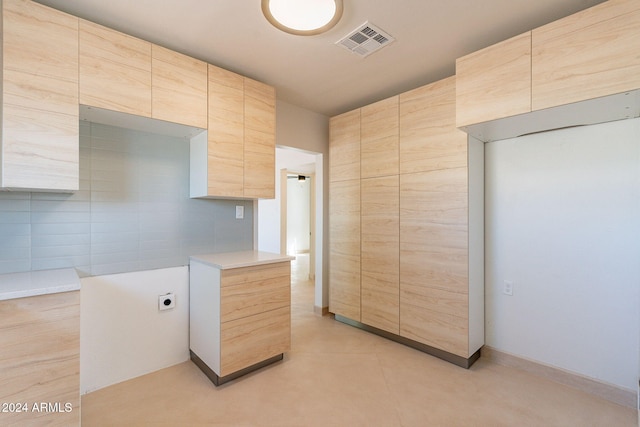 kitchen featuring light brown cabinets and tile walls