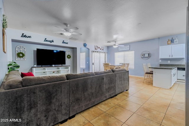 living area with a textured ceiling, visible vents, a ceiling fan, and light tile patterned flooring