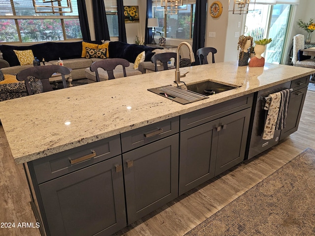 kitchen with light hardwood / wood-style floors, light stone counters, sink, and a wealth of natural light