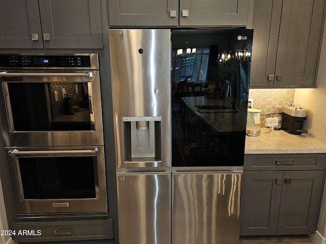 kitchen featuring double oven, gray cabinetry, and fridge with ice dispenser