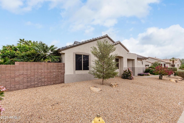 view of front of home with fence, a tiled roof, and stucco siding