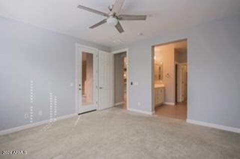 unfurnished bedroom with ceiling fan, light colored carpet, and connected bathroom