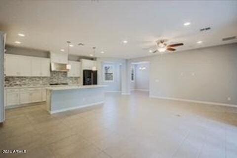 kitchen featuring refrigerator, hanging light fixtures, a kitchen island, and white cabinets