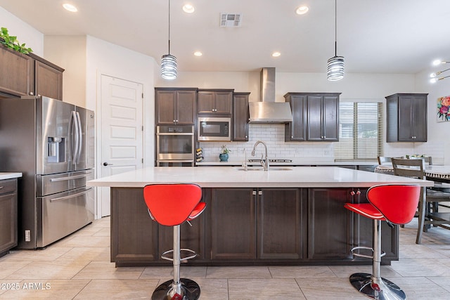22960 N 94th Ln, Peoria, AZ 85383 - kitchen featuring appliances with stainless steel finishes, wall chimney exhaust hood, decorative backsplash, light countertops, and a center island with sink