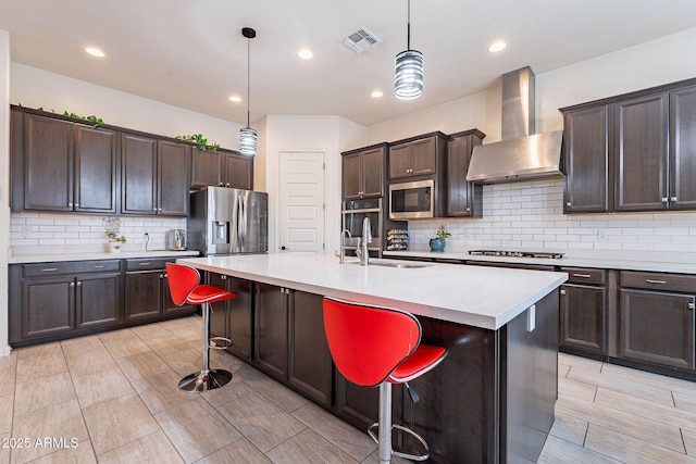 22960 N 94th Ln, Peoria, AZ 85383 - kitchen featuring appliances with stainless steel finishes, wall chimney exhaust hood, dark brown cabinets, a breakfast bar area, and light countertops