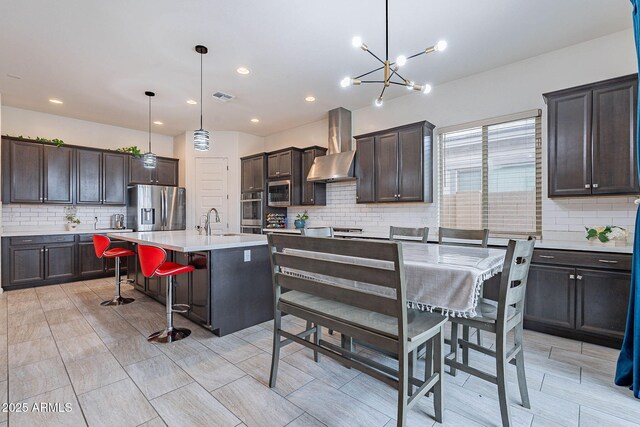 22960 N 94th Ln, Peoria, AZ 85383 - kitchen featuring wall chimney exhaust hood, appliances with stainless steel finishes, tasteful backsplash, dark brown cabinetry, and light countertops