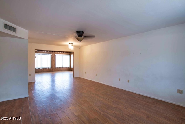 empty room featuring dark wood-style floors, visible vents, ceiling fan, and baseboards