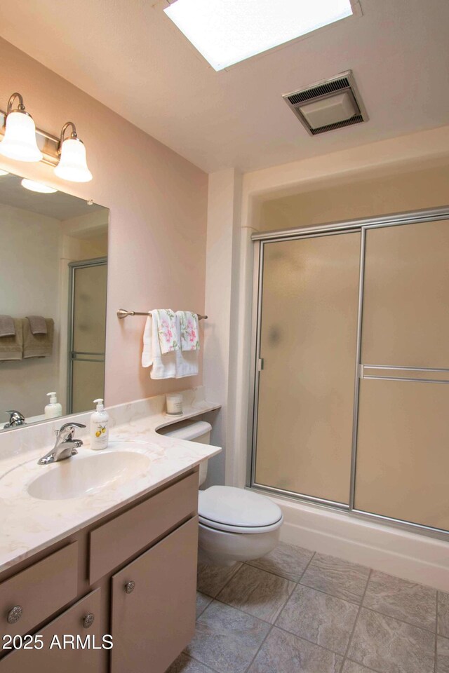 bathroom with toilet, vanity, an enclosed shower, and visible vents