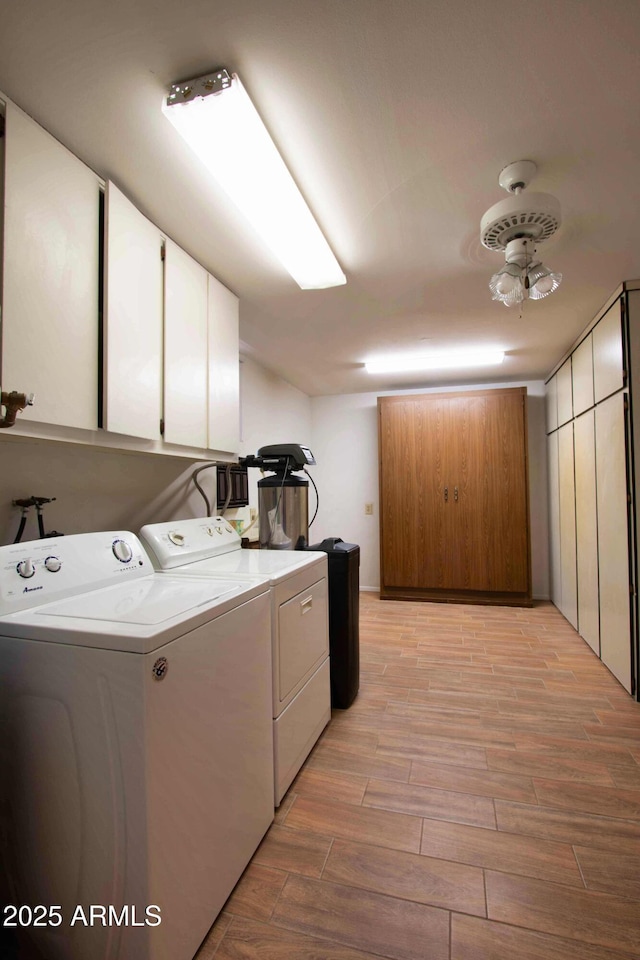 clothes washing area featuring washing machine and clothes dryer, wood finish floors, and cabinet space
