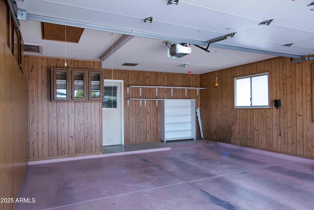 garage with a garage door opener and wooden walls