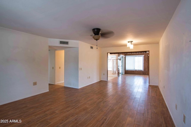 unfurnished room with dark wood-style flooring, baseboards, ceiling fan, and visible vents