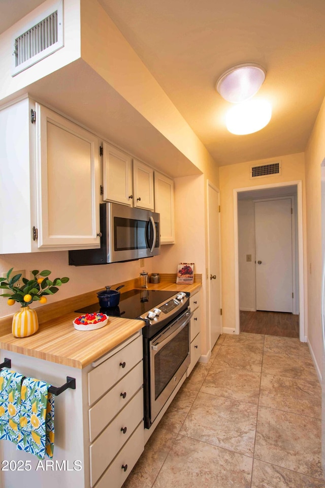 kitchen with white cabinetry, appliances with stainless steel finishes, baseboards, and visible vents