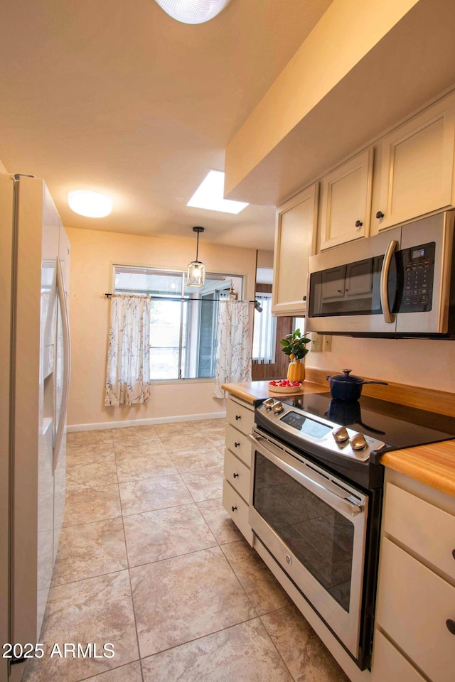 kitchen featuring light tile patterned floors, appliances with stainless steel finishes, baseboards, and pendant lighting