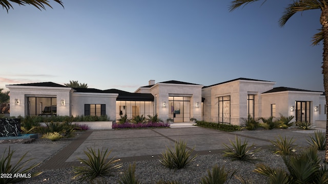 view of front of home featuring stucco siding, concrete driveway, and a chimney