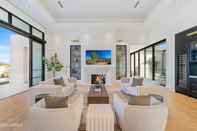 living area with plenty of natural light, light wood-style floors, and a raised ceiling