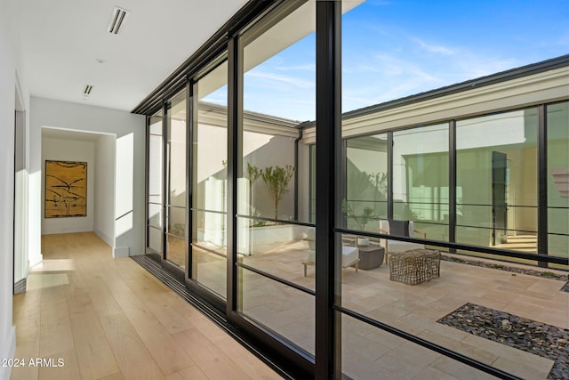 doorway featuring visible vents, floor to ceiling windows, baseboards, and wood finished floors