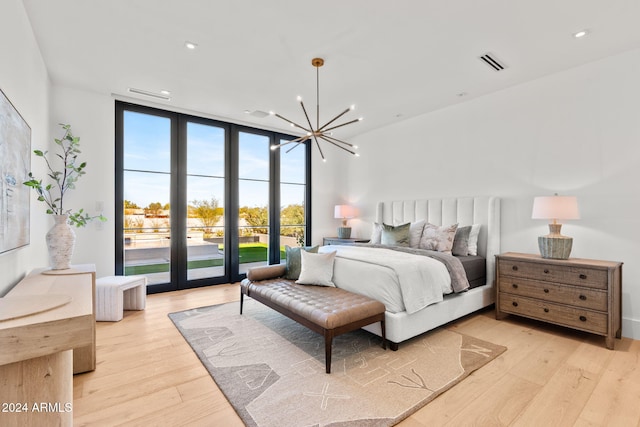 bedroom featuring light wood finished floors, visible vents, expansive windows, a notable chandelier, and access to outside