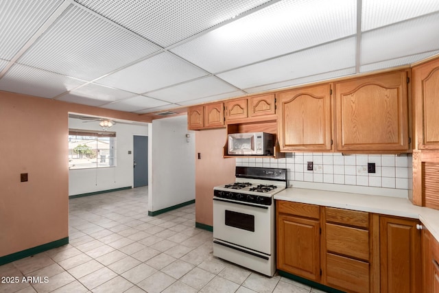 kitchen featuring tasteful backsplash, white appliances, ceiling fan, and a drop ceiling