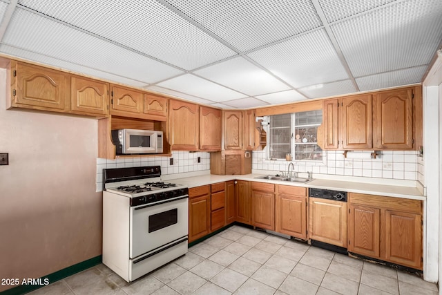 kitchen with light tile patterned flooring, sink, backsplash, white appliances, and a drop ceiling