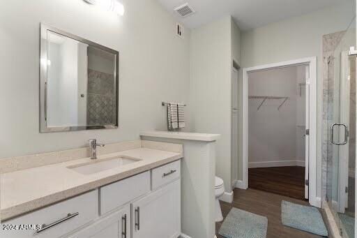 bathroom with wood-type flooring, an enclosed shower, vanity, and toilet