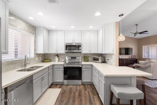 kitchen featuring kitchen peninsula, a breakfast bar area, stainless steel appliances, hanging light fixtures, and sink