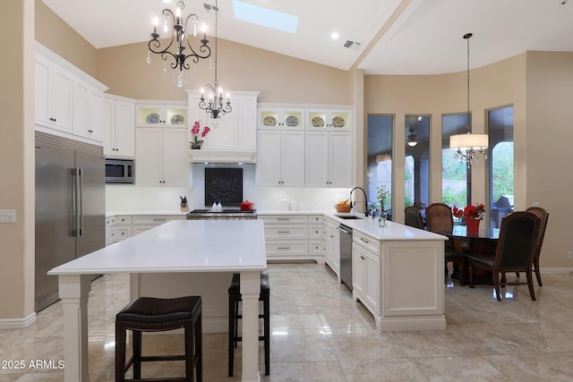 kitchen featuring kitchen peninsula, a kitchen bar, a skylight, sink, and built in appliances