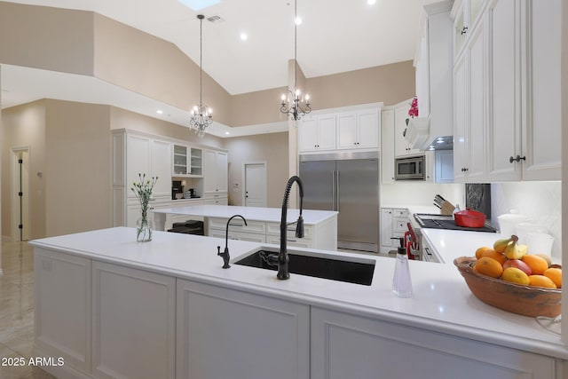 kitchen with pendant lighting, white cabinets, sink, built in appliances, and a chandelier