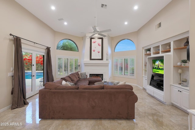 living room featuring ceiling fan, a towering ceiling, a fireplace, and french doors