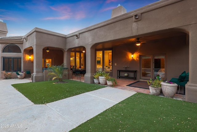 back house at dusk with a patio area and a yard