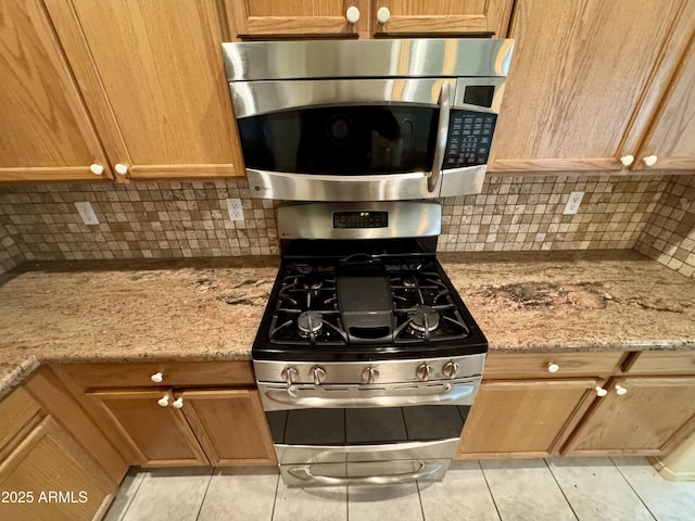 kitchen with backsplash, light stone countertops, and appliances with stainless steel finishes