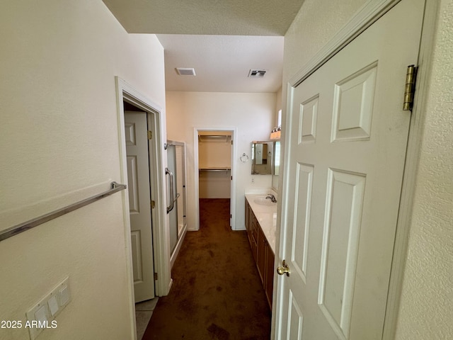 hallway with dark carpet and sink