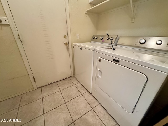 clothes washing area with light tile patterned floors and washer and clothes dryer