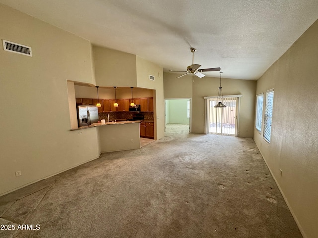 unfurnished living room featuring ceiling fan, high vaulted ceiling, light carpet, and a textured ceiling