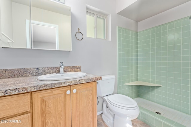 bathroom with tiled shower, vanity, and toilet