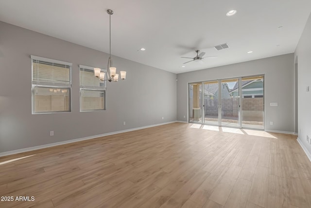 empty room featuring ceiling fan with notable chandelier and light hardwood / wood-style floors