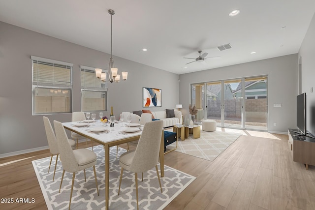 dining area with ceiling fan with notable chandelier and light hardwood / wood-style flooring