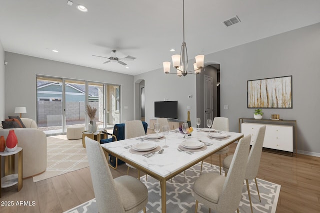 dining room featuring ceiling fan with notable chandelier and light hardwood / wood-style flooring