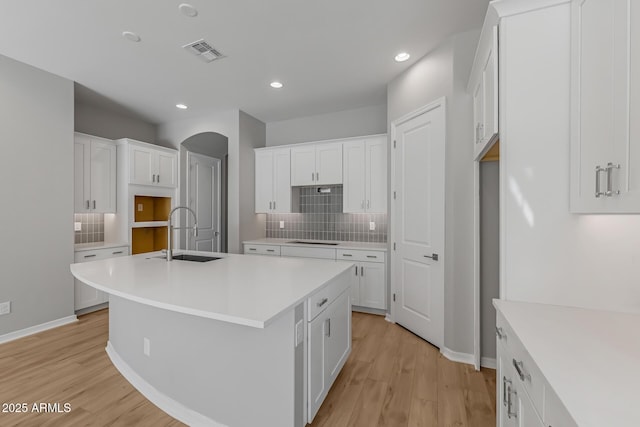 kitchen with white cabinets, sink, and an island with sink