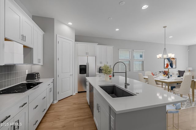 kitchen featuring a center island with sink, pendant lighting, sink, and stainless steel appliances