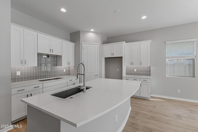 kitchen featuring white cabinets and an island with sink