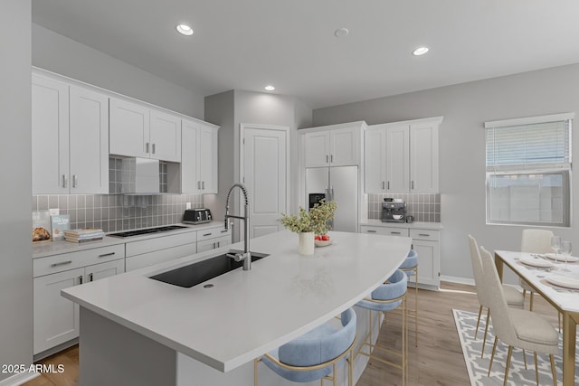 kitchen featuring white cabinets, stainless steel refrigerator with ice dispenser, and a kitchen island with sink