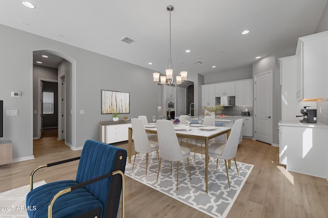 dining area featuring light hardwood / wood-style flooring, a notable chandelier, and sink