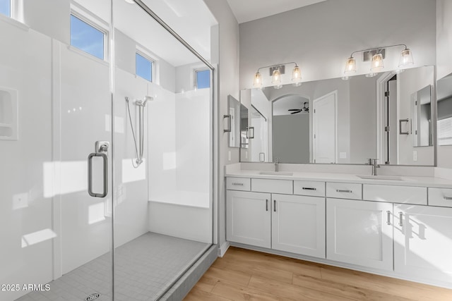 bathroom with ceiling fan, vanity, an enclosed shower, and hardwood / wood-style flooring