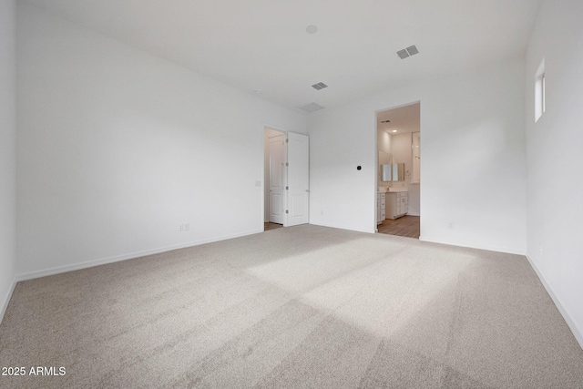 unfurnished bedroom featuring carpet flooring, ensuite bathroom, and baseboards