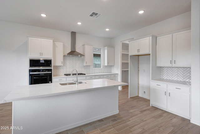 kitchen with visible vents, appliances with stainless steel finishes, white cabinetry, and wall chimney range hood