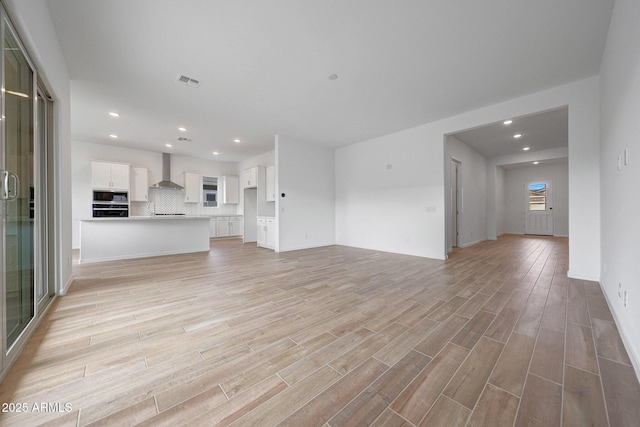 unfurnished living room featuring light wood-style flooring, recessed lighting, and visible vents